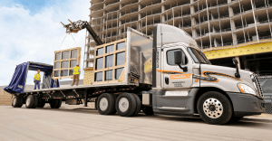 A semi truck transporting a massive window frame on its trailer.